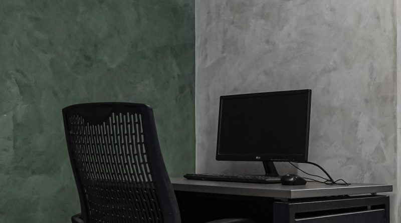 Simple modern office interior with a mesh chair and desk against textured walls.